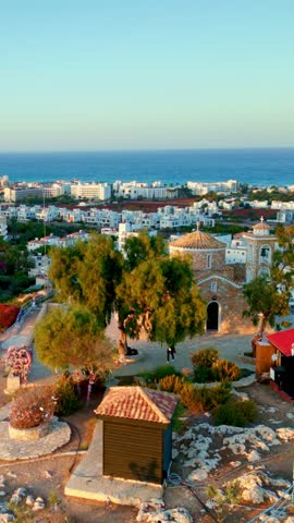 Vertical drone video of a small church made from stone on a rocky hill with a picturesque view of the sea in Protaras, Cyprus