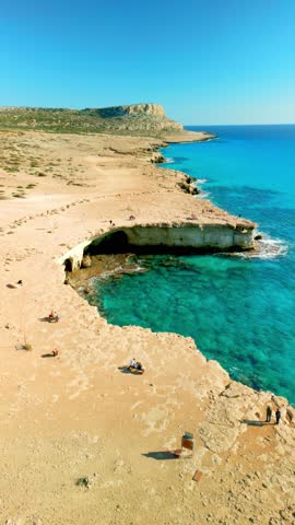 Vertical drone video of a picturesque coast with rocks and sea caves, with a view at Cape Greco, attraction for diving and cliff jumping in Cyprus