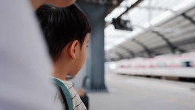 Close-up of a young Asian boy and mother waiting for a commuter train at the platform while wearing a green backpack at train station. - Powered by Shutterstock - Get 15% off with code: PIKWIZARD15