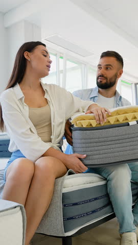 Couple Examining Mattress Features in Furniture Showroom