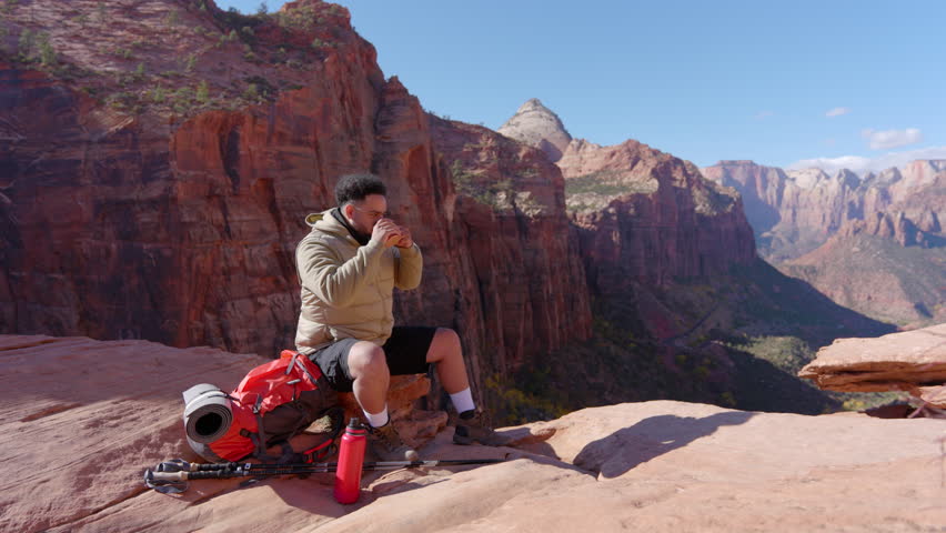 Dedicated African American hiker is fully immersed in the breathtaking and stunning views at Zion National Park, surrounded by the incredibly majestic and iconic red rock formations area is known for