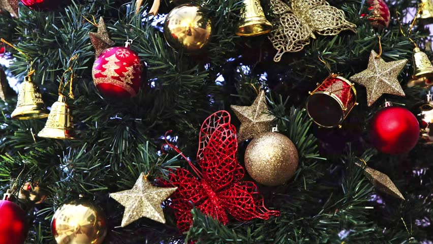 A tree with many ornaments on it, including a butterfly and a bell. The tree is decorated for Christmas