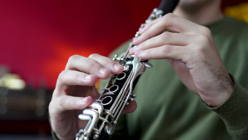 Clarinet player. Clarinetist hands playing flute woodwind music instrument closeup at home, soft focus. Musical instruments. Guy plays the oboe in education classroom. Hobby. 