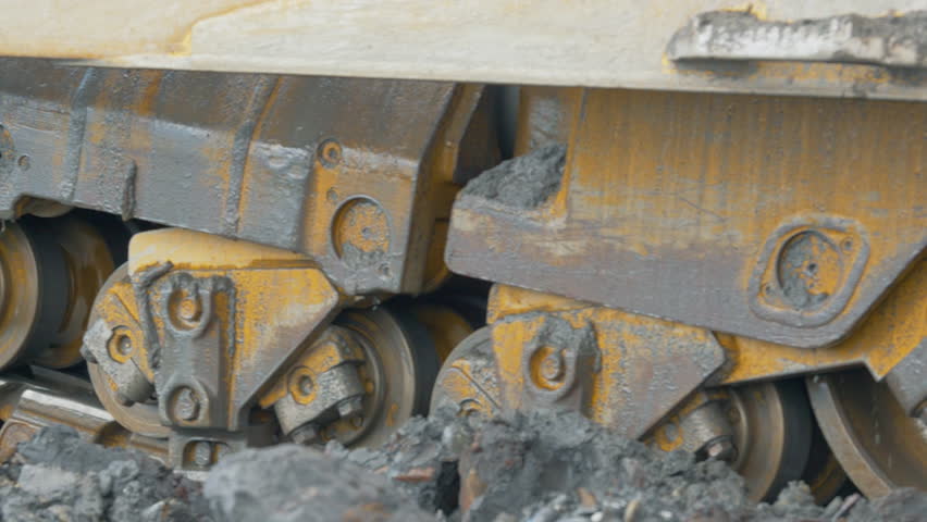 Industrial mining equipment moving on the tracks at the quarry. Mining equipment transporting the material using the tracks. Mining equipment carrying the collected rocks on the tracks.