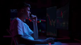 Stressed crypto trader touching head with hands while looking at multiple computer monitors showing falling stock market charts in dark room illuminated by blue neon lights. Shooting in slow motion. - Powered by Shutterstock - Get 15% off with code: PIKWIZARD15