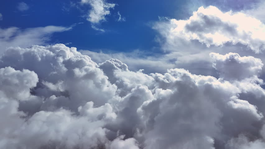 Clouds parting to reveal blue sky over a serene landscape on a bright day