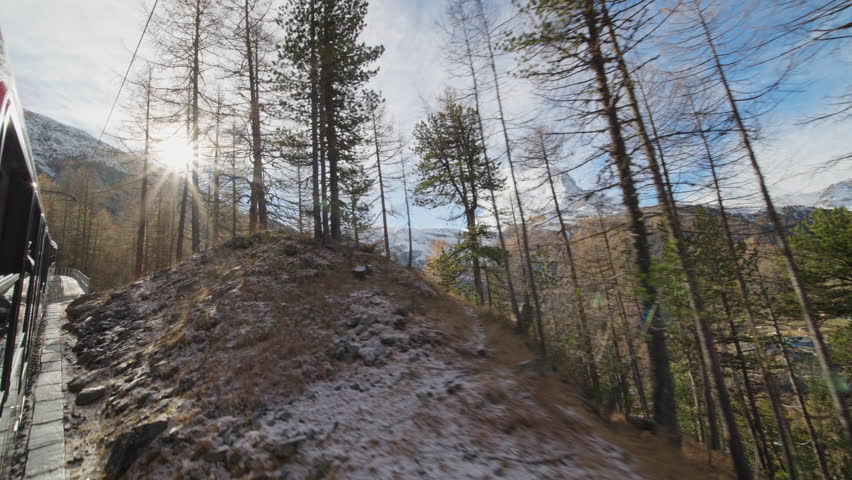 Gornergrat bahn railway running towards summit station with Matterhorn mountain peak background in Zermatt on a sunny winter day. Swiss Alps, Switzerland travel journey trip Shot from train window.