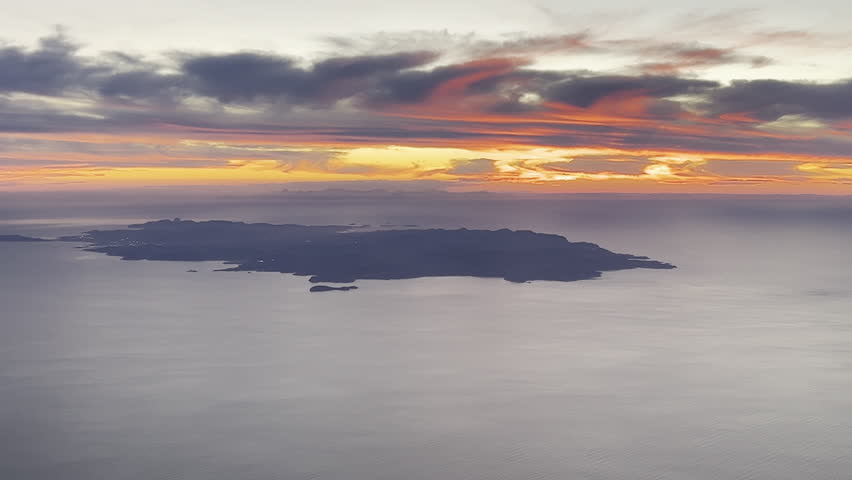 Elevated aerial view of Ibiza Island, Balearic Islands, Spain, recorded at sunset from an airplane cockpit with some clouds in the sky. 4K