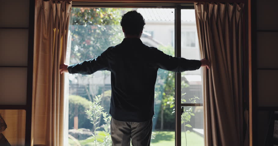Open curtains, back and man in house, morning and start day with sunlight, calm and Japanese. Person, apartment and guy with weekend break, wake up and relax with window, comfort and accommodation