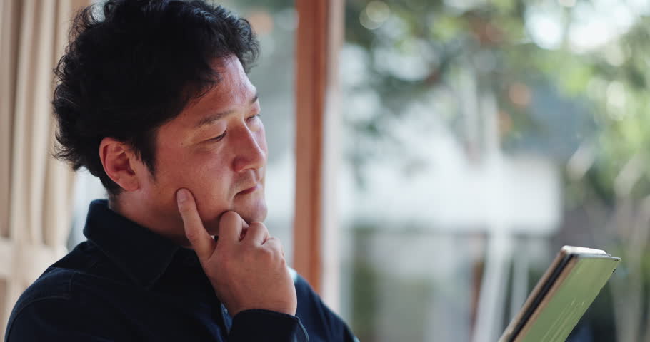 Thinking, tablet and Asian man in home for remote work, connection and networking. Living room, freelancer and Japanese person on digital tech for website, research and reading online news in morning