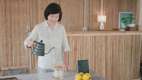 Asian senior woman pouring hot water for drip coffee in bamboo house, brewing fresh drip coffee in the morning, the quiet process of making tea or coffee, brewing coffee and sitting on the balcony - Powered by Shutterstock - Get 15% off with code: PIKWIZARD15