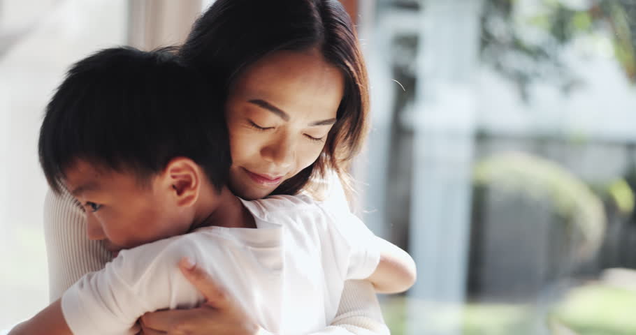 Happy, hug and Asian mom with child in home for bonding, love and healthy relationship by window. Family, childhood and Japanese mother with boy embrace for affection, care and support in house