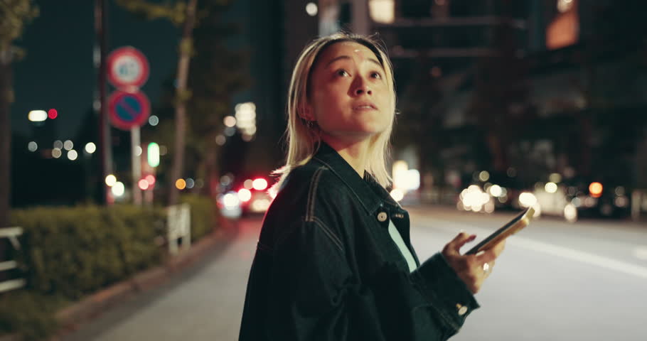 Night, woman or phone in city for travel, social media or map app for journey in Tokyo. Japanese girl, crossing road or tech in town for searching, online transport service and status update at bokeh