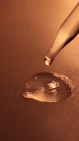 Amber glass bottle with a dropper releasing a droplet, set against a bold yellow backdrop for a modern aesthetic.
