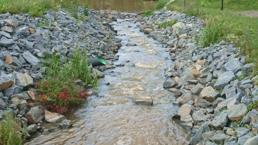 Urban Flood Control System with Stone-Lined Channel During Heavy Flow. Engineering solution featuring riprap protection and stormwater management in action