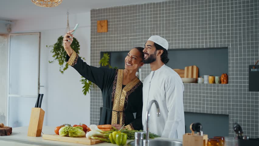 Couple from emirati spending time together inside their beautiful apartment. Domestic lifestyle moments  of an emirati man in white kandura and woman in black abaya.