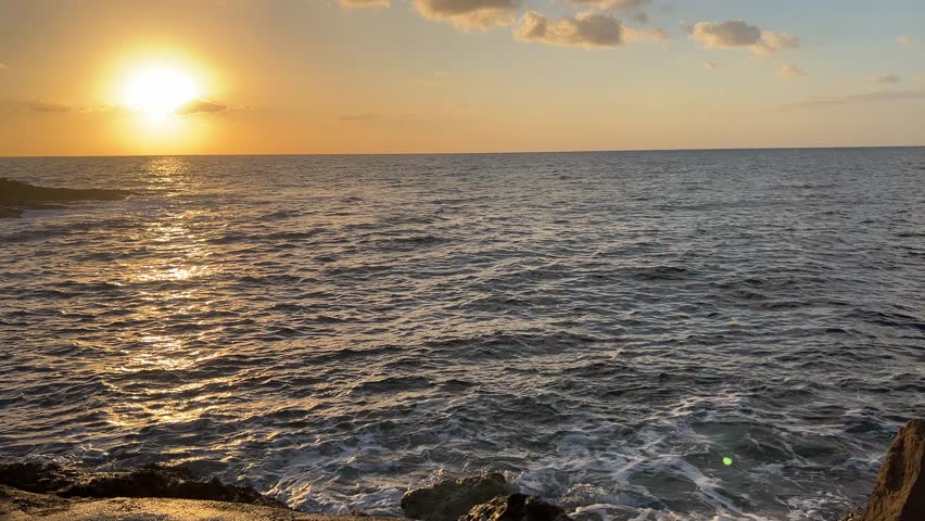 Sunset on Kissonerga beach in Paphos district of Cyprus on the Mediterranean Sea. The movement of sea waves against the background of the sunset.