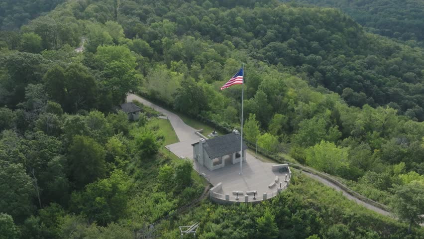 Rotating aerial view of USA flag waving at Grandad Bluff in Wisconsin, USA on windy day.