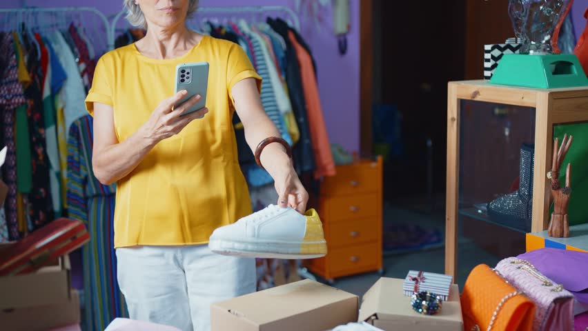 Senior woman selling clothes and accessories online with a selling app from home.