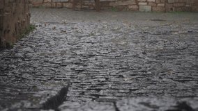 A rainsoaked cobblestone street lined with weathered ancient walls creates a distinct atmosphere - Powered by Shutterstock - Get 15% off with code: PIKWIZARD15