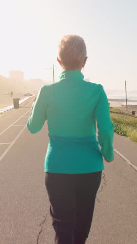 71 year old woman gets her exercise at the beach in Southern California. Vertical Video.