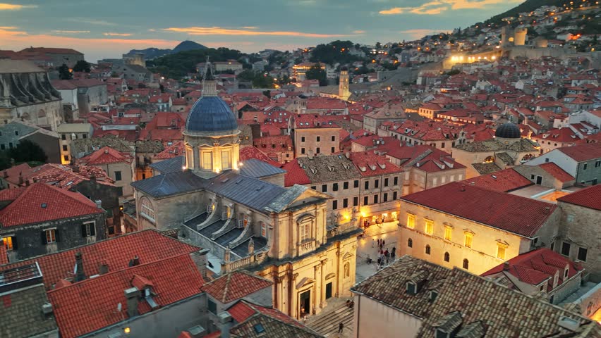 Sunset over historic city of Dubrovnik, Croatia showcasing red rooftops and ancient architecture. Aerial shot of Dubrovnik old town, Cathedral of the Assumption of the Virgin Mary