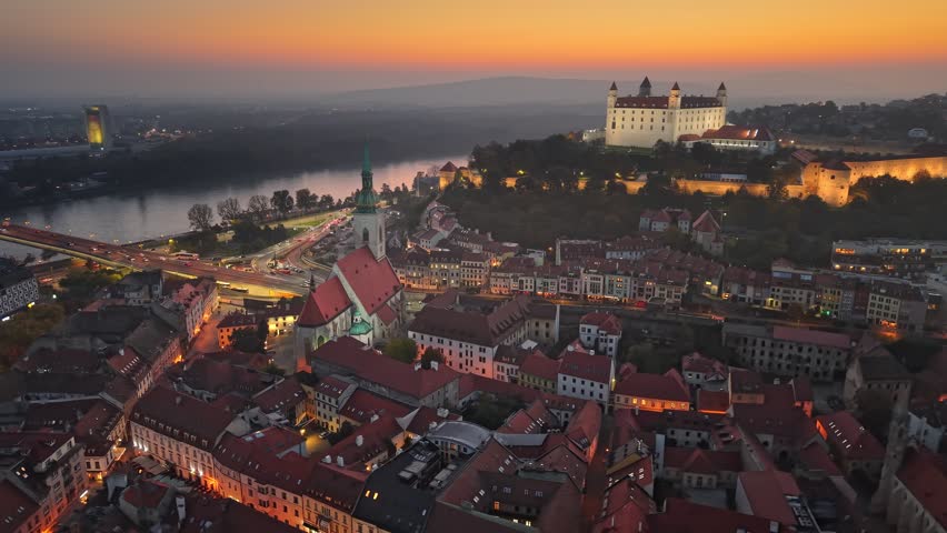 Aerial evening sunset view of Bratislava old town and Bratislava Castle or Bratislavsky Hrad. Cental part of Bratislava with city lights and orange sunset sky, Slovakia