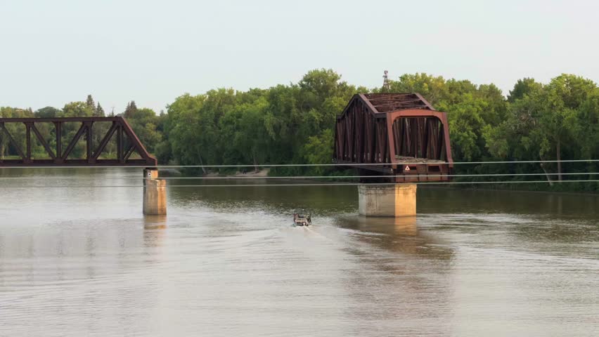 Cityscape, red river in Winnipeg, Manitoba, summer, warm evening, the railway bridge over the river is turned in the middle of the river. Big river at sunset with blue water.