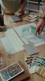 Vertical high angle view of two unrecognisable coworkers developing interior design of house using colour palettes and samples of materials on wooden table - Powered by Shutterstock - Get 15% off with code: PIKWIZARD15