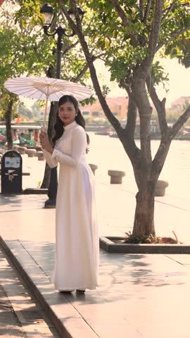 A beautiful Asian bride in a stunning wedding dress with a white parasol outdoor