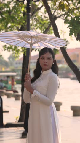 A beautiful Asian bride in a stunning wedding dress with a white parasol outdoor