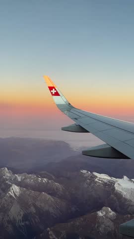 Airplane wing flying over snowy mountains