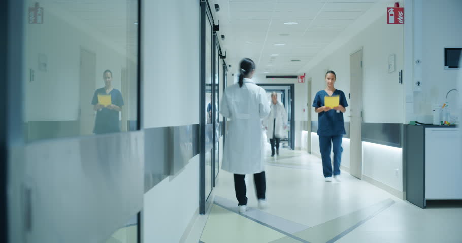 Timelapse Footage of a Busy Hospital Hallway with Doctors, Nurses and Specialists Working in Hospital. Female and Male Physicians, Surgeons, Healthcare Officials Walk Together in Corridor