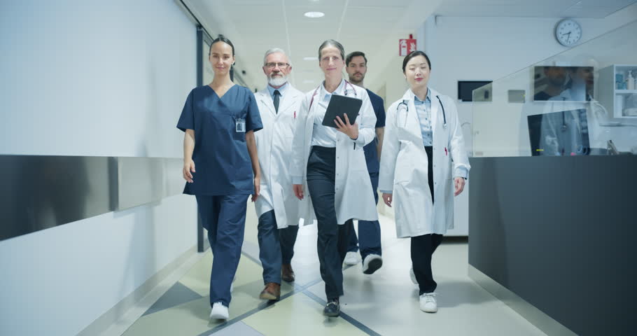Group of Young and Senior Male and Female Physicians, Doctors, Surgeons, Nurses, General Practitioners, Posing in a Hospital Hallway, Walking Together, Ready to Save Lives. Slow Motion Footage