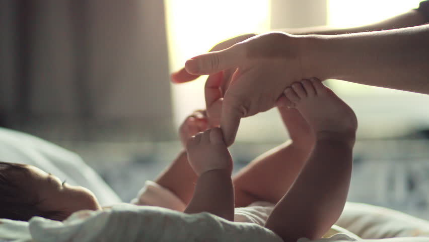 Little hand of child baby girl holding hand of mother, A newborn holds on to mom