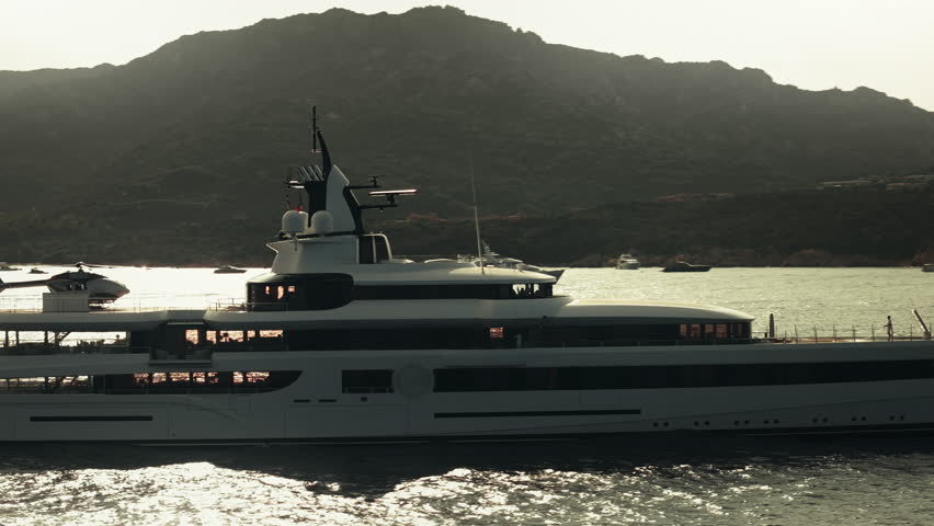 Aerial view of a luxury billionaire megayacht with a helicopter sitting on the helipad in the coast of Sardinia, Italy