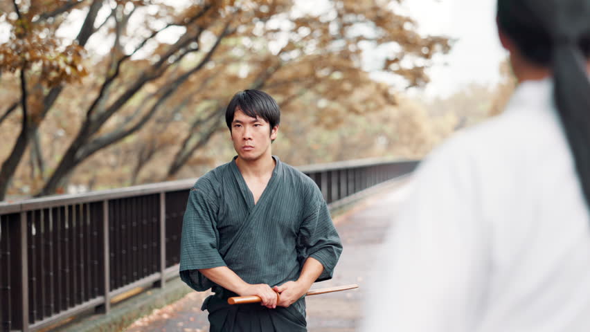 Wood, sword and Japanese man in martial arts training, culture and traditional sports on bridge at park. Bamboo katana, samurai and practice outdoor, aikido exercise or battle technique with partner