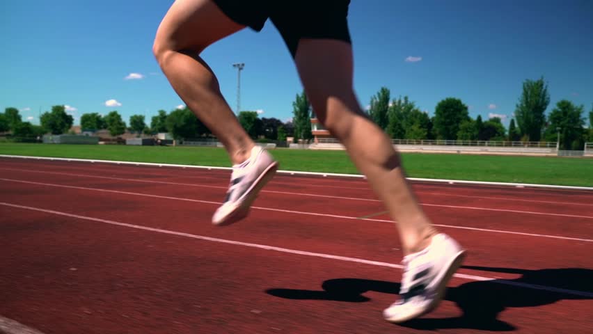 Close up legs Young man wearing sportswear running on track at sport stadium. Fit man jogging outdoor cross the finish line. Exercise in the morning. Healthy and active lifestyle concept.