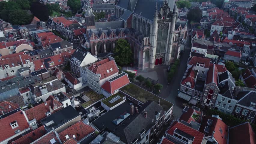 A drone footage of smoke coming out of a red booth next to Hooglandse Kerk church with a street view and urban buildings in Leiden, the Netherlands