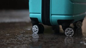 Close-up video of blue suitcase wheels rolling through a puddle on a rainy autumn day. The wet pavement reflects the falling rain, creating a moody seasonal atmosphere, video 4k - Powered by Shutterstock - Get 15% off with code: PIKWIZARD15