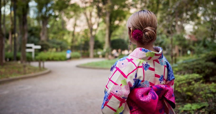 Japanese, back and girl with kimono in park for culture travel, indigenous clothes and nature sightseeing. Woman, walking and fashion with spiritual vacation, traditional morning and history in Japan