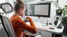 Designer drinks coffee in comfortable modern workplace and watches as artificial intelligence generates an image on monitor screen on theme of Christmas holiday. AI helps to find creative solutions. - Powered by Shutterstock - Get 15% off with code: PIKWIZARD15