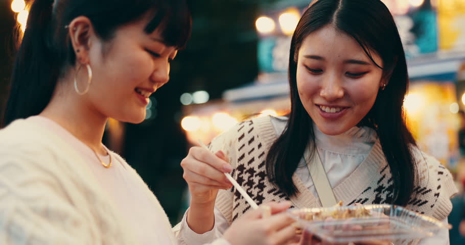 Friends, food and eating for street market, bonding and conversation with celebration in Japan at night together. Women, talking and laughing in Tokyo for culture, festival and community with travel