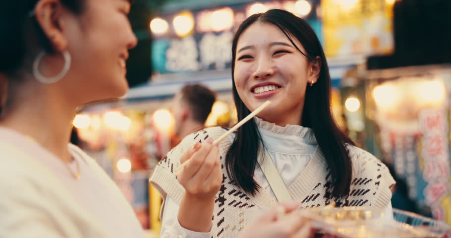 Friends, food and eating for street market, bonding and conversation with celebration in Japan at night together. Women, talking and laughing in Tokyo for culture, festival and community with travel