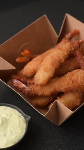 Hot crispy shrimp breaded with salt and spices with white sauce on a dark concrete background