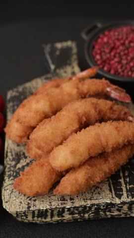 Hot crispy shrimp breaded with salt and spices with white sauce on a dark concrete background