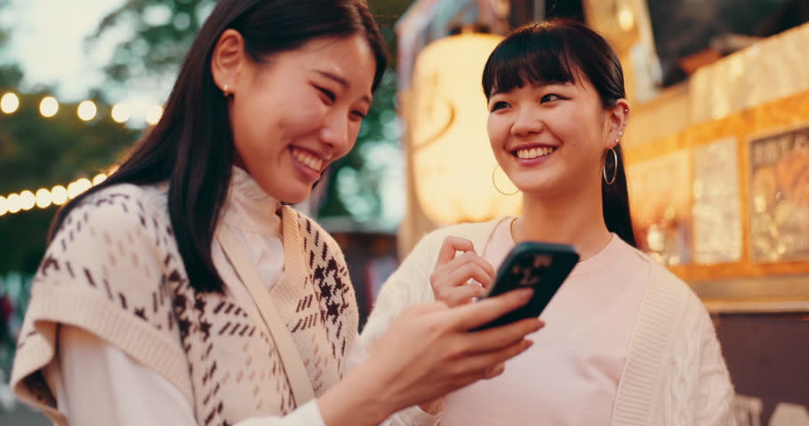 Laughing, friends and Japanese women with smartphone, city and funny videos on app, browsing and digital. Mobile, smile and bonding with gossip, social media and people on holiday, humor and Japan