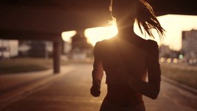 A young sporty woman runner is listening to music in earphones and training workout. Slim fitness girl is jogging outdoor. Concept of workouts running and healthy sport lifestyle - Powered by Shutterstock - Get 15% off with code: PIKWIZARD15