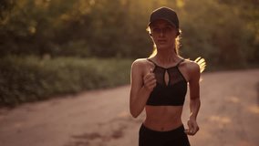 A young sporty woman runner is listening to music in earphones and training workout. Slim fitness girl is jogging outdoor. Concept of workouts running and healthy sport lifestyle - Powered by Shutterstock - Get 15% off with code: PIKWIZARD15