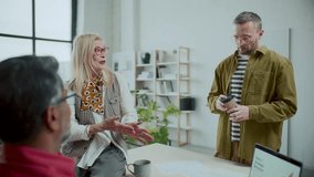 Senior business lady having talk with two diverse male coworkers during coffee break in modern office with minimalist interior - Powered by Shutterstock - Get 15% off with code: PIKWIZARD15